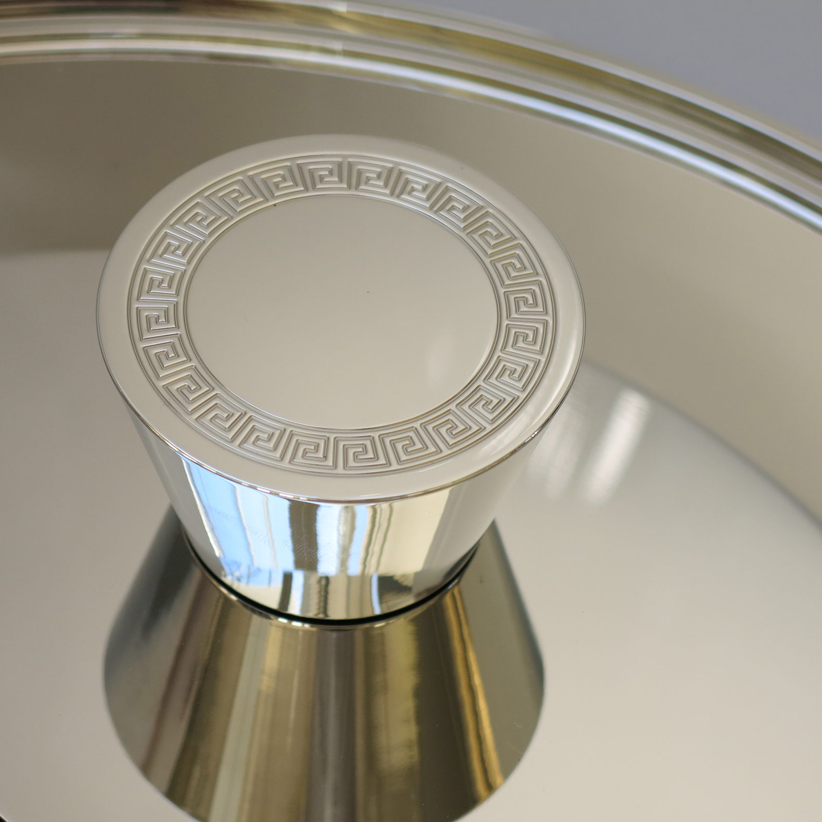 Modern flare door knob by H. Theophile in polished nickel with a Greek Key pattern engraved around the perimeter of its face.